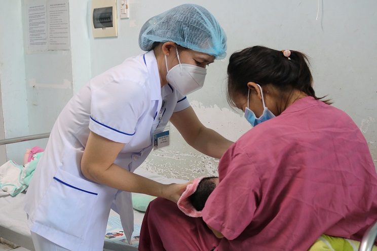 Nhân viên y tế hướng dẫn bà mẹ cho trẻ bú đúng cách.