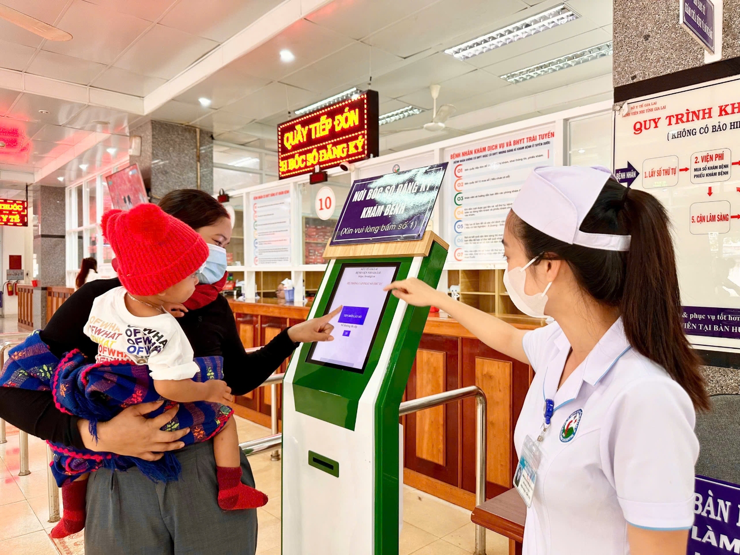 Cán bộ y tế Bệnh viện Nhi Gia Lai hướng dẫn bệnh nhân đăng ký khám bệnh bằng hệ thống y tế thông minh.